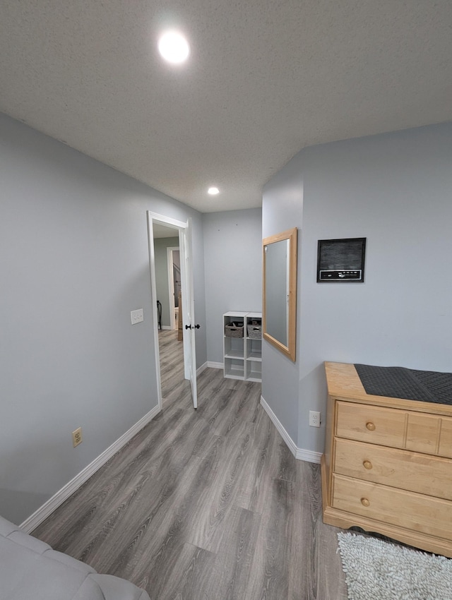 bedroom featuring a textured ceiling and light hardwood / wood-style flooring