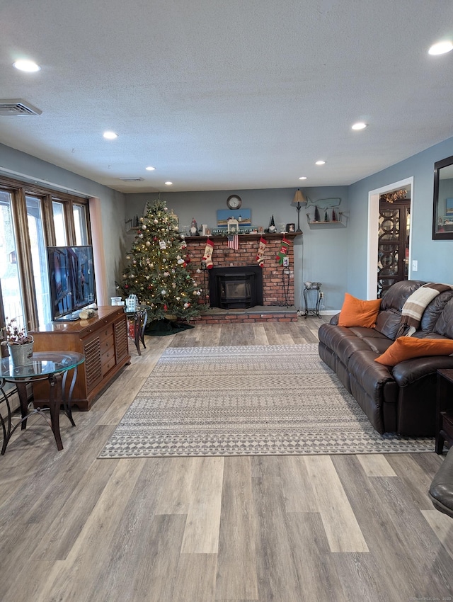 living room with a wood stove, wood-type flooring, and a textured ceiling