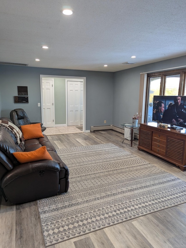 living room with baseboard heating, light wood-type flooring, and a textured ceiling