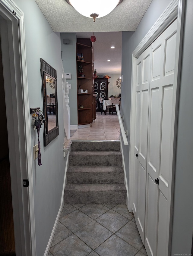 stairs with a textured ceiling and tile patterned floors