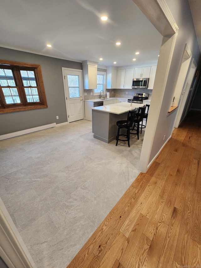 kitchen with sink, a breakfast bar area, a kitchen island, stainless steel appliances, and white cabinets