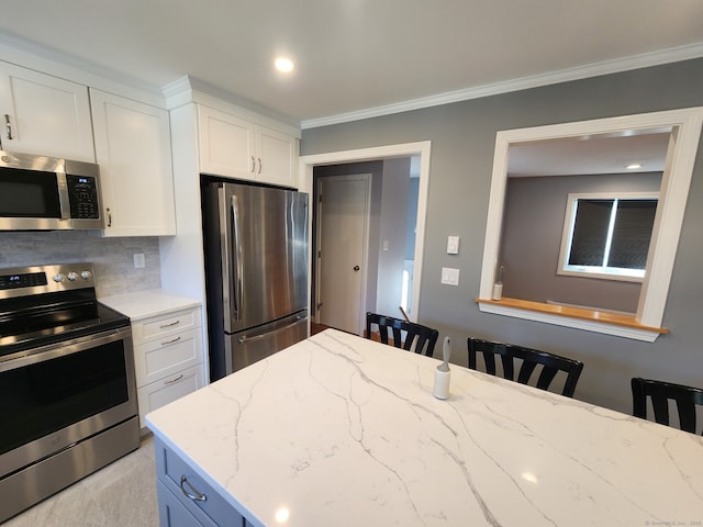 kitchen with a breakfast bar area, light stone counters, crown molding, appliances with stainless steel finishes, and white cabinets