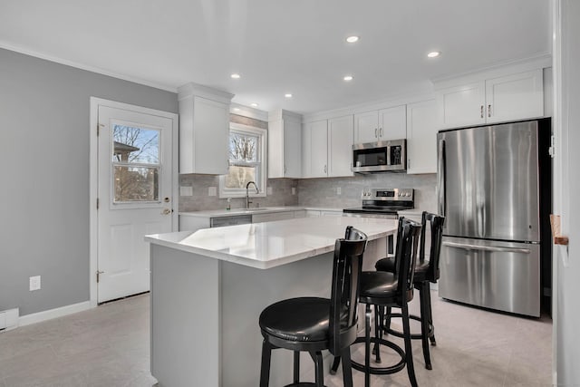 kitchen with white cabinetry, a breakfast bar, stainless steel appliances, and a center island