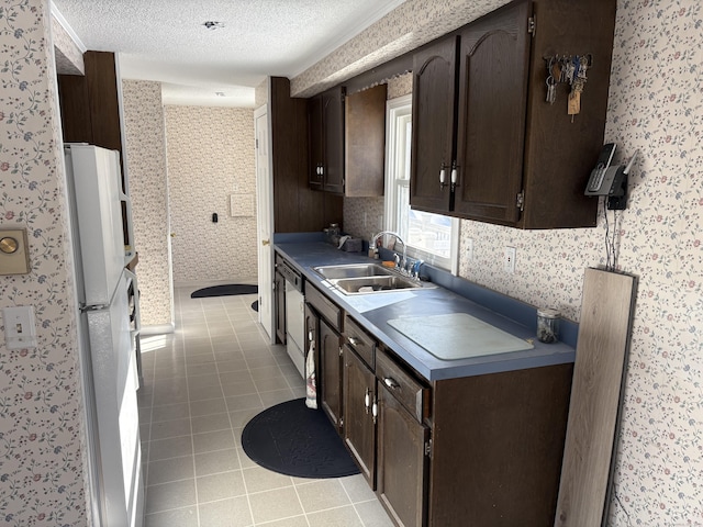 kitchen featuring sink, dark brown cabinetry, a textured ceiling, light tile patterned floors, and white refrigerator