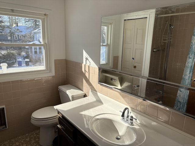 bathroom with tile walls, toilet, vanity, and tiled shower