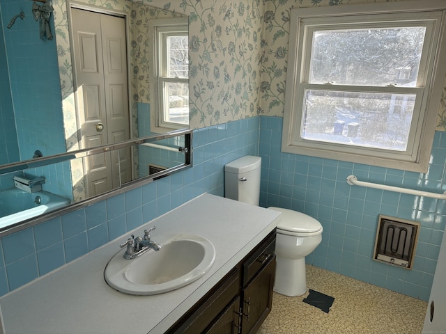 bathroom featuring toilet, tile walls, a bath, and vanity