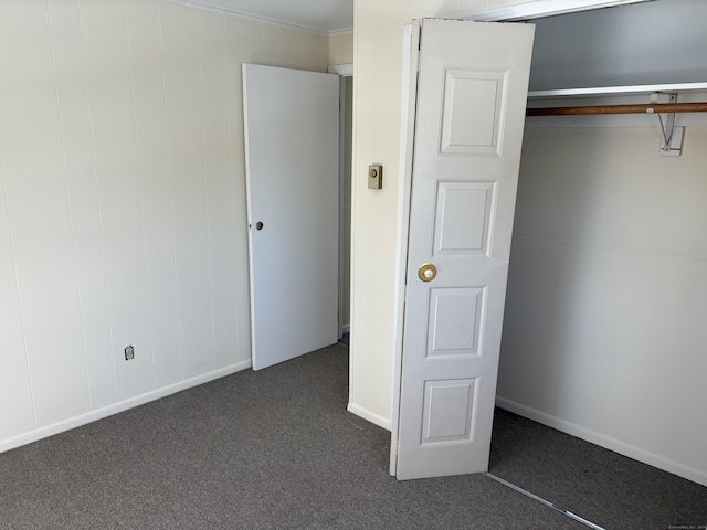 unfurnished bedroom featuring dark colored carpet and a closet