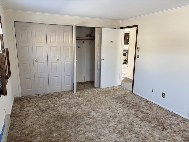 unfurnished bedroom featuring carpet floors, multiple closets, and crown molding