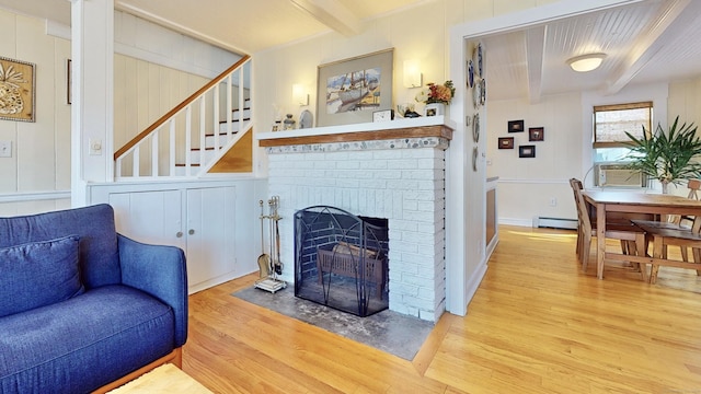 living room with baseboard heating, a fireplace, wood-type flooring, and beamed ceiling