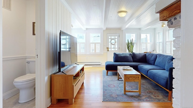 living room featuring light hardwood / wood-style floors, a baseboard heating unit, and beamed ceiling