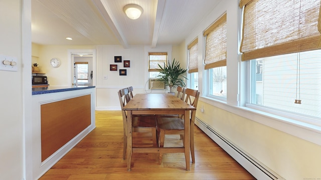 dining room featuring light wood-type flooring, baseboard heating, and beamed ceiling