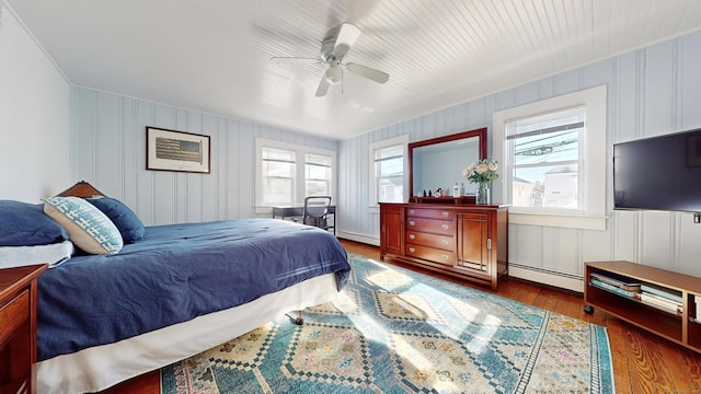 bedroom featuring ceiling fan, a baseboard heating unit, and dark hardwood / wood-style floors