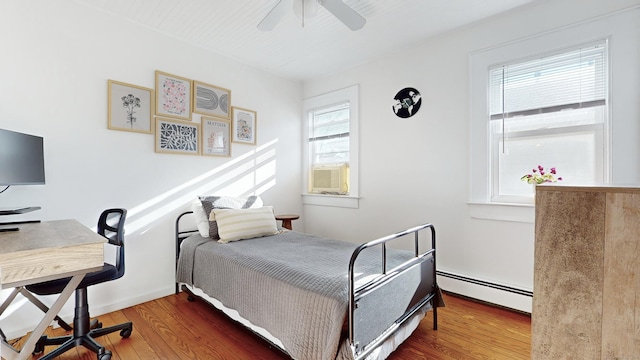 bedroom with baseboard heating, hardwood / wood-style floors, and ceiling fan