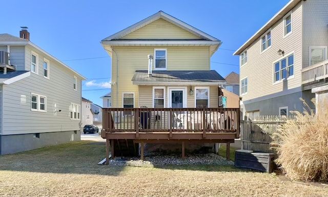 back of property with a wooden deck and a lawn