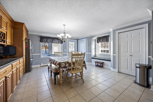 tiled dining area with an inviting chandelier, ornamental molding, a textured ceiling, and a baseboard heating unit