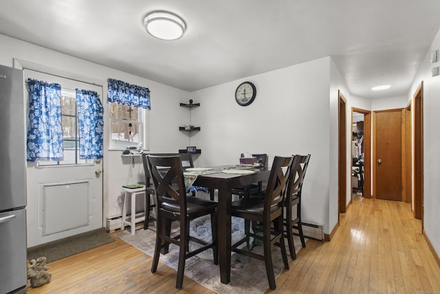 dining room with baseboard heating and light hardwood / wood-style flooring