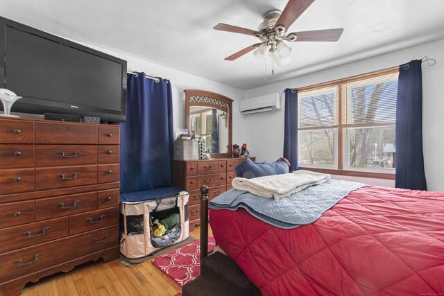 bedroom featuring a wall mounted air conditioner, hardwood / wood-style floors, ceiling fan, and a wood stove