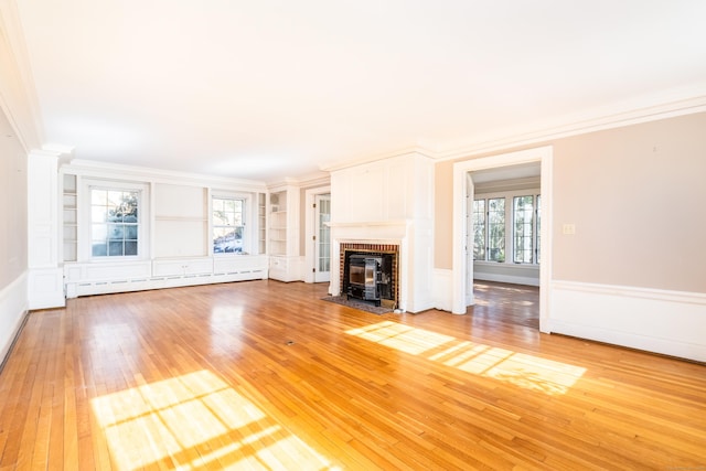 unfurnished living room with crown molding, baseboard heating, built in features, and light wood-style floors