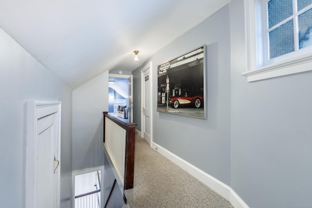 hall with baseboards, vaulted ceiling, carpet flooring, and an upstairs landing