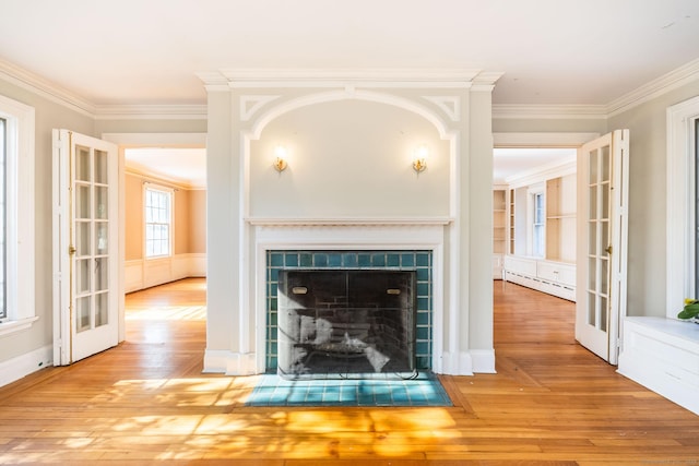 unfurnished living room with hardwood / wood-style flooring, crown molding, french doors, a fireplace, and a baseboard heating unit