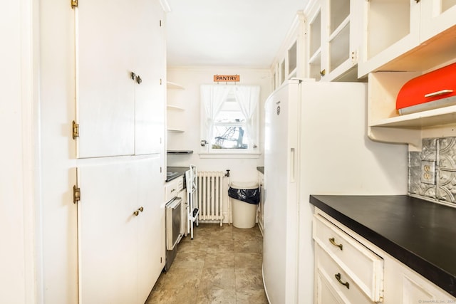 kitchen featuring open shelves, dark countertops, radiator heating unit, glass insert cabinets, and white cabinetry