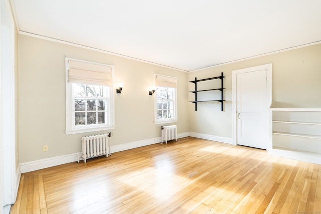 empty room with radiator heating unit, hardwood / wood-style flooring, and baseboards