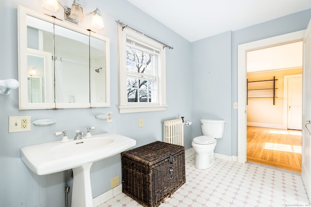 bathroom with baseboards, tile patterned floors, toilet, and radiator