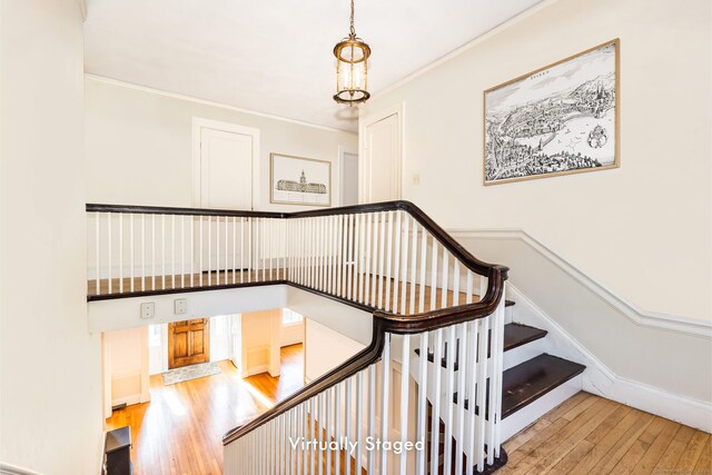 staircase with a towering ceiling, wood-type flooring, baseboards, and crown molding