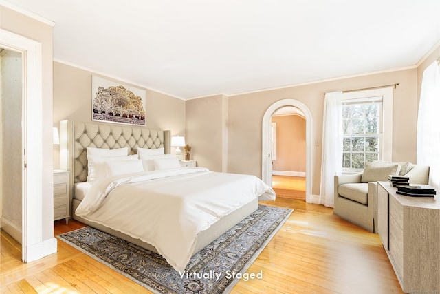 bedroom featuring arched walkways, crown molding, baseboards, and light wood-style floors