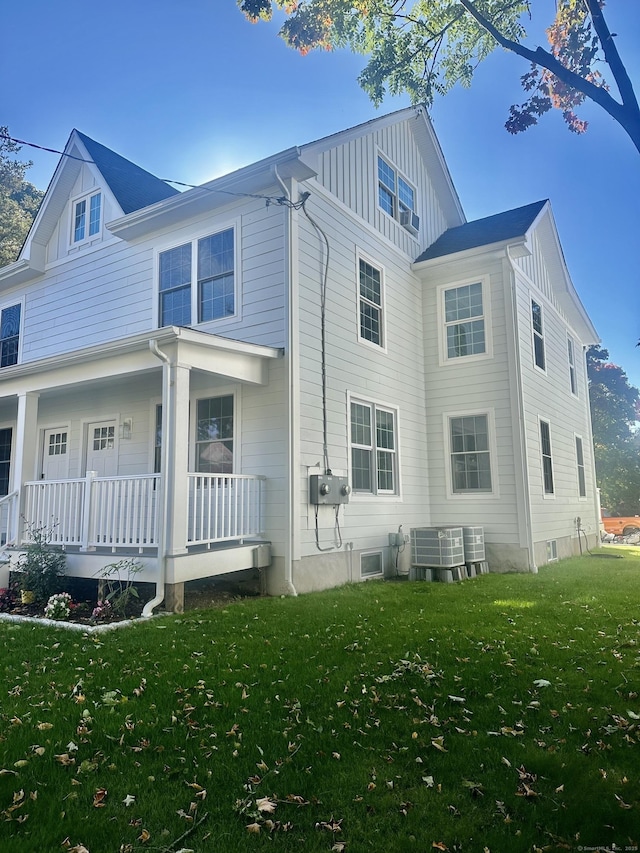 view of side of property featuring cooling unit, a yard, and a porch