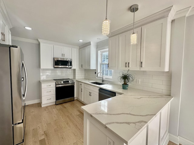 kitchen featuring stainless steel appliances, white cabinets, hanging light fixtures, light stone counters, and sink