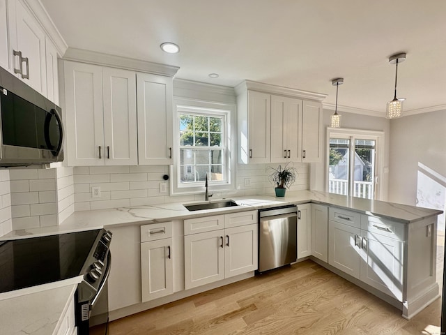 kitchen with decorative light fixtures, appliances with stainless steel finishes, sink, and white cabinetry