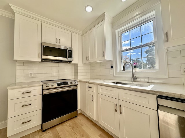 kitchen featuring light hardwood / wood-style floors, sink, white cabinetry, stainless steel appliances, and light stone counters