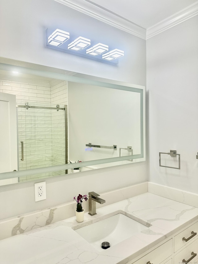 bathroom with a shower with door, vanity, and ornamental molding