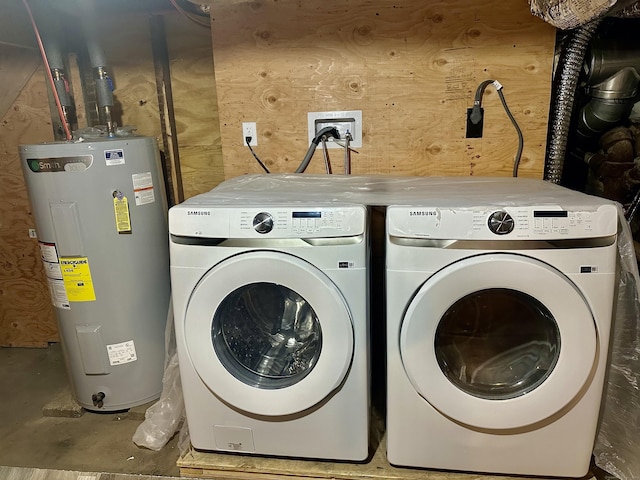 clothes washing area featuring electric water heater, washer and clothes dryer, and wooden walls