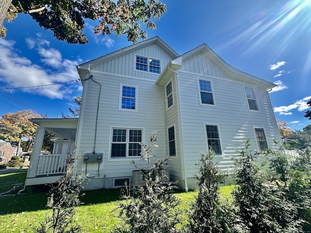 back of property with covered porch and a yard