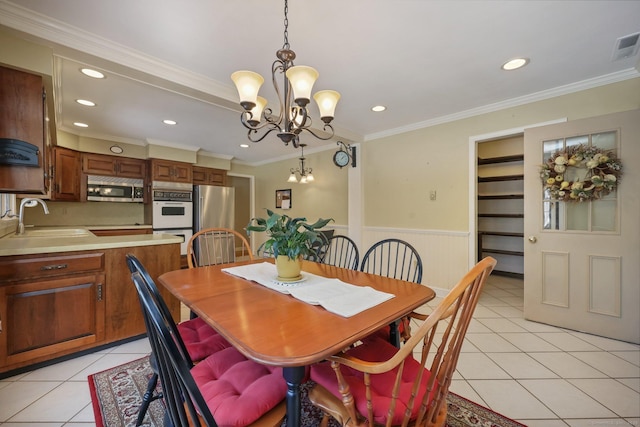 dining space with a notable chandelier, ornamental molding, sink, and light tile patterned floors