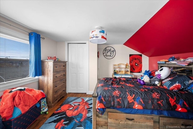 bedroom with vaulted ceiling, dark hardwood / wood-style flooring, and a closet