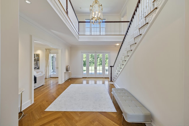 entrance foyer featuring a towering ceiling, an inviting chandelier, ornamental molding, french doors, and parquet floors