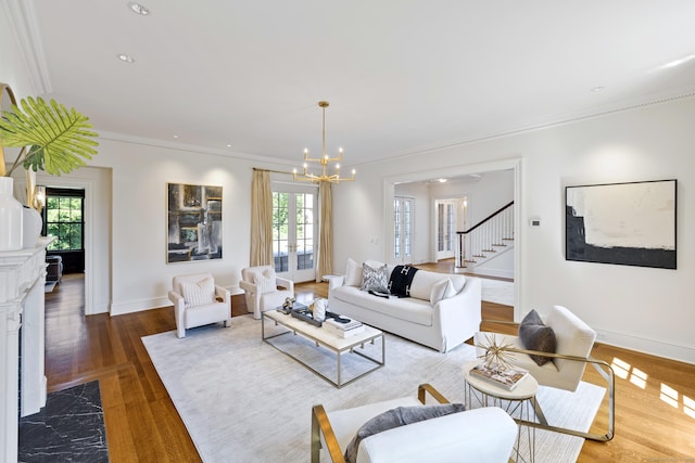 living room featuring french doors, ornamental molding, wood-type flooring, and a notable chandelier