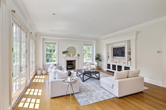 living room with a brick fireplace, ornamental molding, and light wood-type flooring