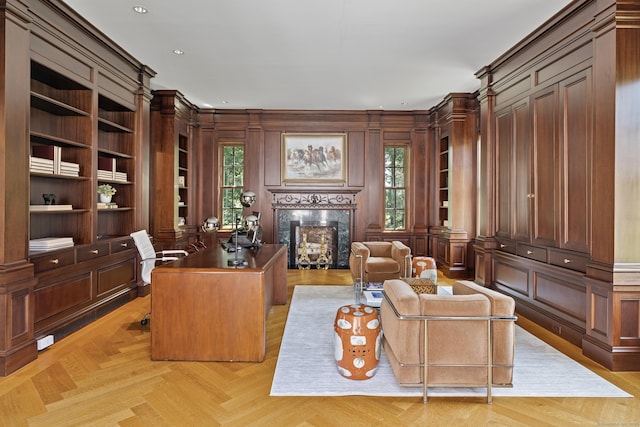 home office featuring a healthy amount of sunlight, a fireplace, light parquet flooring, and built in shelves