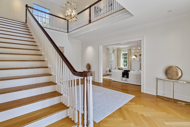 staircase with parquet floors, ornamental molding, and a notable chandelier