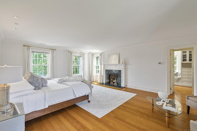 bedroom featuring hardwood / wood-style floors, ornamental molding, and a premium fireplace