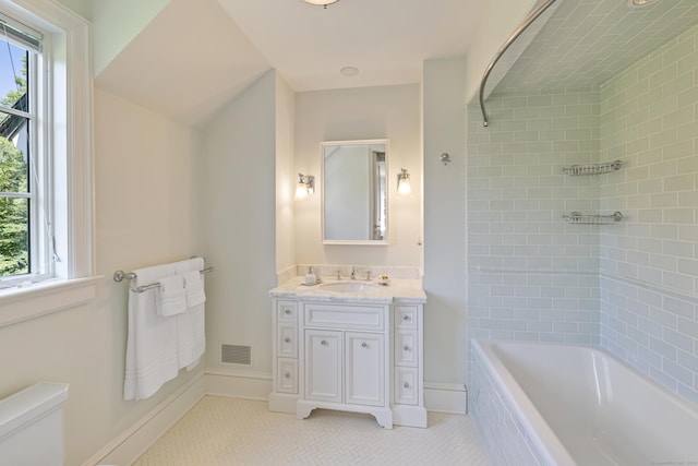 bathroom with a wealth of natural light, vanity, tile patterned floors, and tiled tub