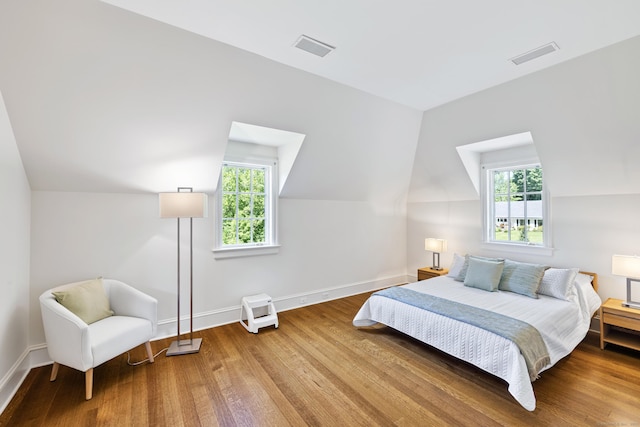 bedroom featuring lofted ceiling, wood-type flooring, and multiple windows