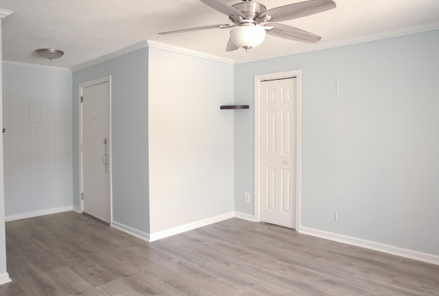 spare room featuring light wood-type flooring, ceiling fan, crown molding, and a textured ceiling