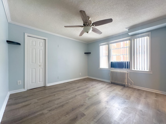 empty room with ornamental molding, radiator, a textured ceiling, and hardwood / wood-style floors