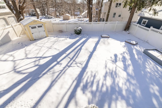 yard layered in snow featuring a storage shed