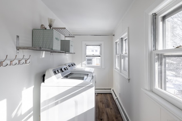 clothes washing area with dark wood-type flooring, washing machine and dryer, and a baseboard heating unit